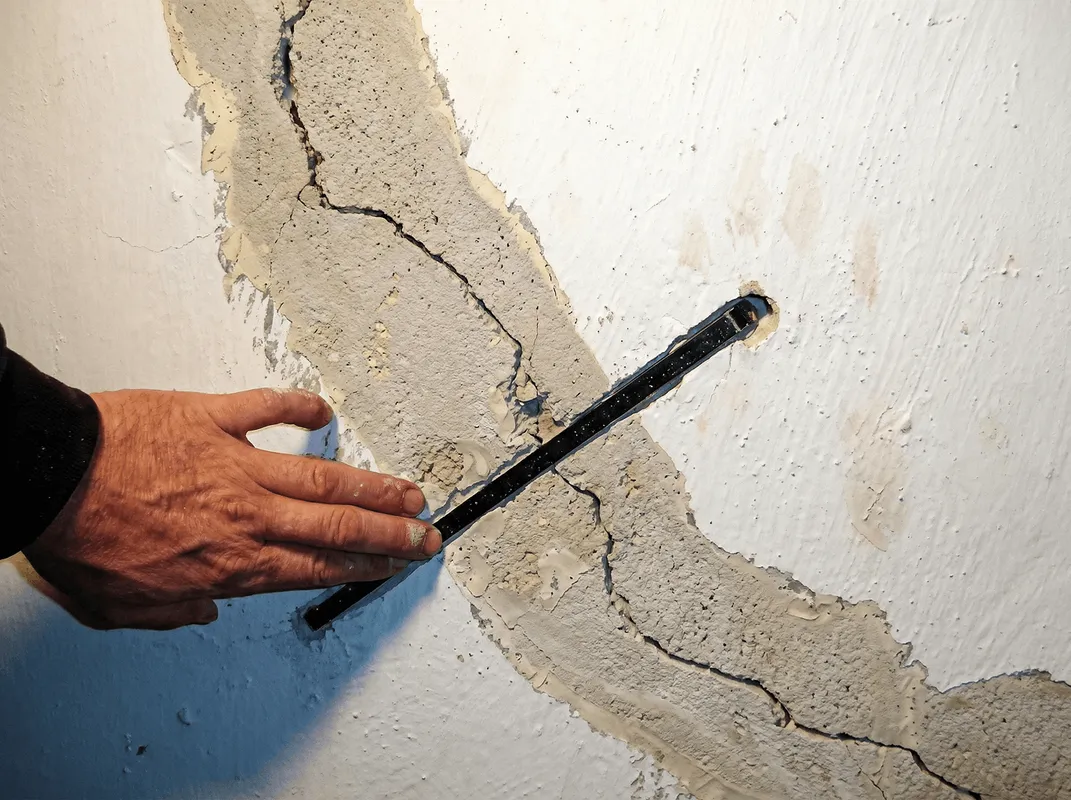 A wall with a large crack is being inspected by a professional in South Bend, IN